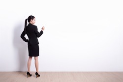Back view of business woman writing something on white wall background, great for your design or text, asian