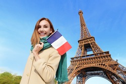 Happy woman travel in Paris with eiffel tower and beautiful blue sky and holding France French flag, caucasian beauty