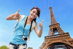 Happy travel woman in Paris with Eiffel Tower and she show thumb up, asian beauty