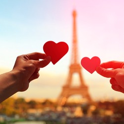 silhouette of romantic lovers hand hold love heart paper with eiffel tower in Paris with sunset