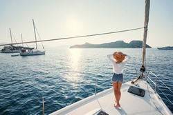 Luxury travel on the yacht. Young happy woman on boat deck sailing the sea. Yachting in Greece.