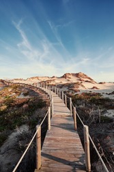 Wooden pedestrian walkway through Sintra-Cascais natural park. Wild sandy landscape, with part of Cresmina Dunes. Beautiful scenery in Portugal.