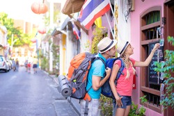 Travel and shopping. Young traveling couple with backpacks choose postcards in souvenir shop in Thailand.