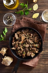 Slow cooked pulled beef in frying pan on wooden background. Top view, flat lay