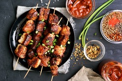 Bbq meat on wooden skewers on plate. Top view, flat lay