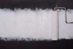 paint roller with white paint on dark wall background