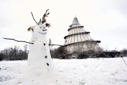  Snowman on a meadow in a Park in Magdeburg in Winter. In the background the millennium tower.                              