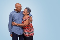 Elderly couple standing, hugging and looking at each other. Light blue gradient background