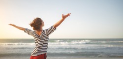 happy young woman enjoying freedom with open hands on sea