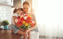 happy mother's day! child daughter congratulates mother and gives a bouquet of flowers to tulips