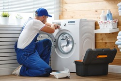 working man plumber repairs a washing machine in   laundry