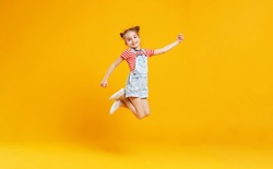 funny child girl jumping on a colored yellow background
