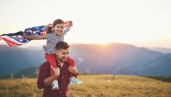  happy family father and child with flag of united states enjoying sunset on nature