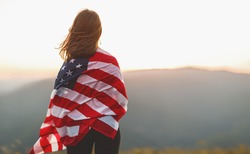 young happy woman with flag of united states enjoying the sunset on nature