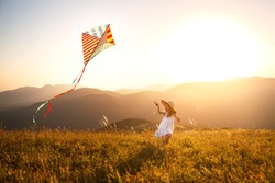 happy child girl running with a kite at sunset outdoors
