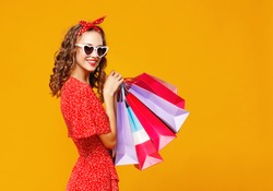 concept of shopping purchases and sales of happy young girl with packages   on yellow background