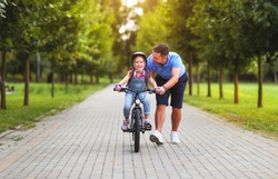 happy family father teaches child daughter to ride a bike in the Park in nature
