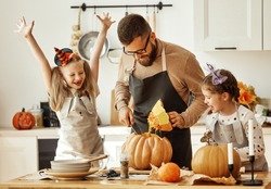 happy family   father  and children daughters prepare for Halloween by carving pumpkins at home in the kitchen