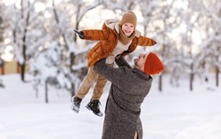 Father lifting little son up while having fun together outdoor on frosty day, happy dad and kid playing in winter park, enjoying snowy weather, actively spending New year holidays on fresh air
