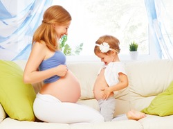 happy family. Pregnant mother and baby daughter having fun relaxing and playing on the sofa at home