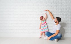 concept. Dad measures the growth of her child daughter at a blank brick wall