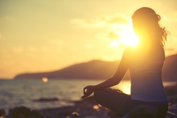 yoga in the beach. woman meditating in lotus pose  at sunset