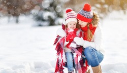 happy family mother and child daughter on a winter walk outdoors drinking tea