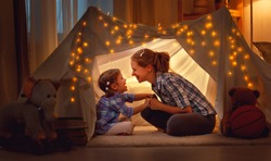 happy family mother and daughter playing at home in a tent 