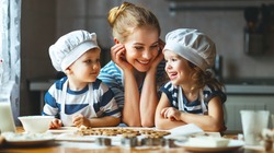 happy family in the kitchen. mother and  children preparing the dough, bake cookies