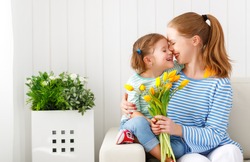Happy mother's day! Child daughter congratulates moms and gives her a postcard and flowers tulips
