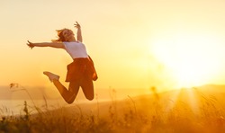 Happy woman   jump,  rejoices, laughs  on sunset in nature 