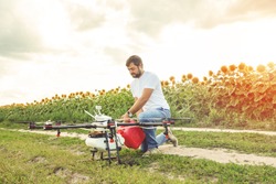 Young man pours fertilizer for irrigation in agriculture drone. Octocopter flight preparation.