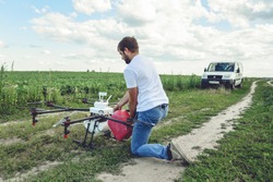 View from the back process of preparing agro drones for irrigation. A man agronomist pours liquid into a Octocopter .