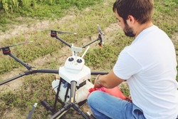 View from the back process of preparing agro drones for irrigation. A man agronomist pours liquid into a Octocopter .