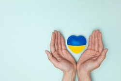 Heart with print the national flag of ukraine in female hands. Flat lay.