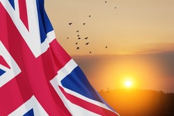 National flags of United Kingdom with flying birds on sunset sky background. Background with place for your text. 3d rendering.