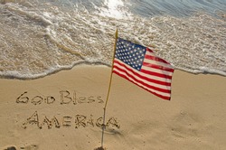 God Bless America written in beach sand with American flag
