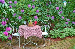 white table and chairs in rhododendron garden with fruit basket on checkered tablecloth