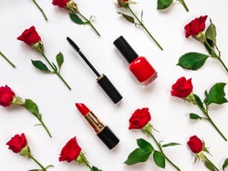 Colorful composition with red bright roses, cosmetics, woman accessories. Flat lay on white table, top view