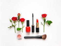 Decorative flat lay composition with woman cosmetics and red rose flowers. Flat lay, top view on white background, make up composition