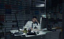 Young business executive working in the office late at night, deadlines and overtime work concept