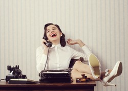 Cheerful woman talking on phone at desk