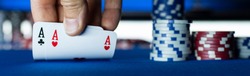Poker tournament at casino: a player is holding two ace cards