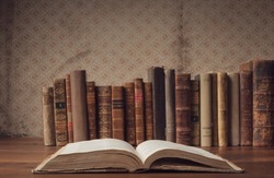 Open book and collection of old books on a desk, knowledge and education concept