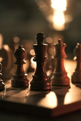 Chess pieces on the chessboard and golden dim light, chess games and strategy concept