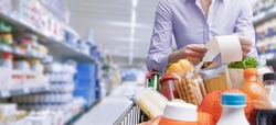 Woman pushing a cart and checking a grocery receipt, grocery shopping and expenses concept