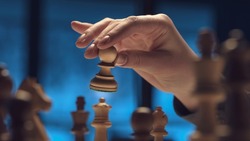 Professional player moving a pawn on the chessboard, strategy games concept