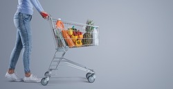 Young woman pushing a full shopping cart, supermarket and grocery shopping banner, blank copy space