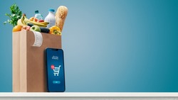Grocery shopping app and grocery bag full of goods: online grocery shopping and home delivery concept, copy space