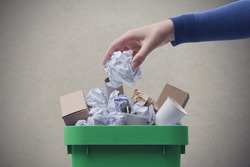 Woman putting paper in the waste bin, separate waste collection and recycling concept